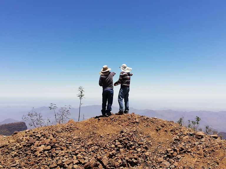 Photograph of the Peruvian landscape, with two people standing on a pile of soil and rocks and looking and pointing into the distance (© Matt Smith)
