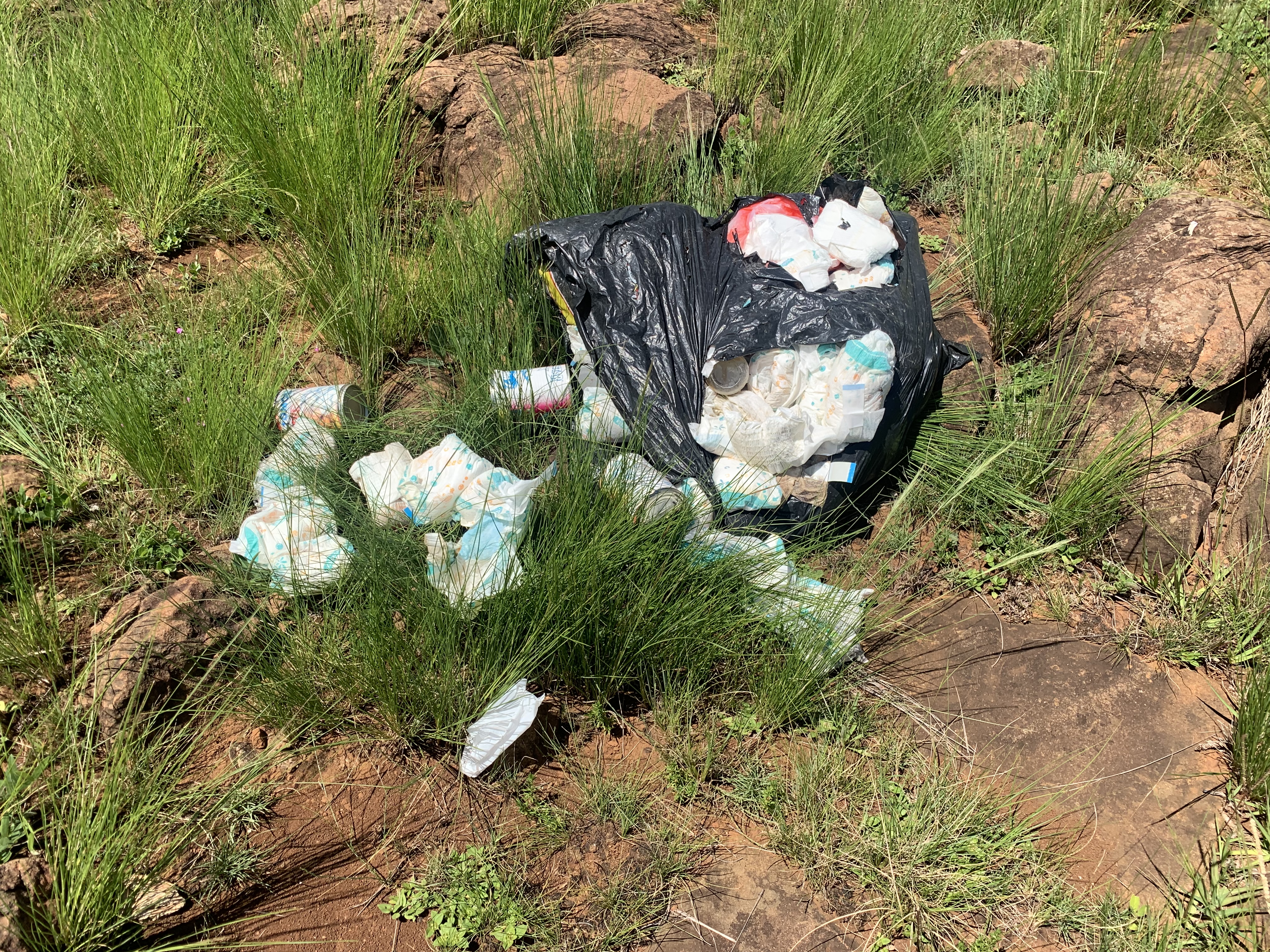 Disposable nappy waste spilling out of black bin bag