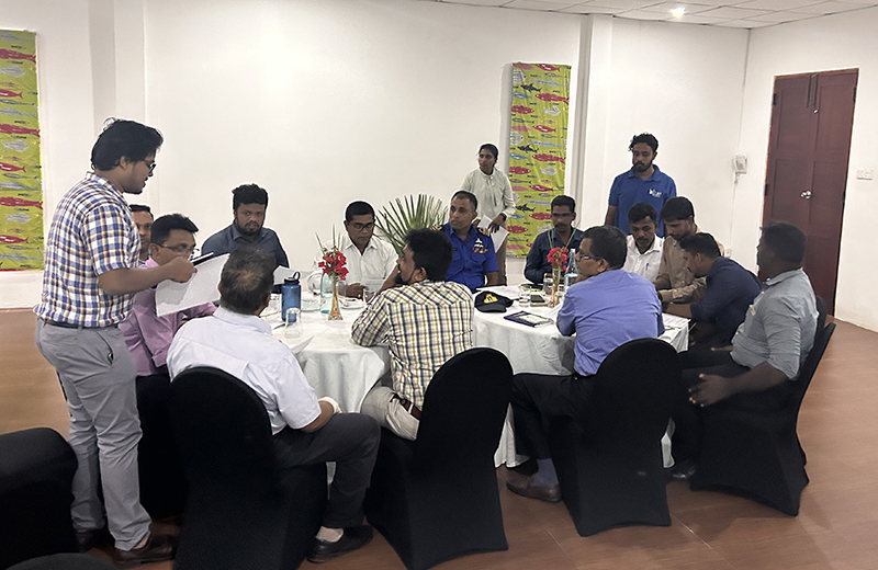 Photograph of participants at a workshop in Sri Lanka. The photograph shows a group of 16 people seated and standing around two circular tables. 