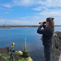 A fieldworker using a laser rangefinder from a jetty to measure the flight height of a bird