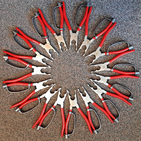 A photograph of a set of bird ringing pliers, arranged in a circle on a brown background